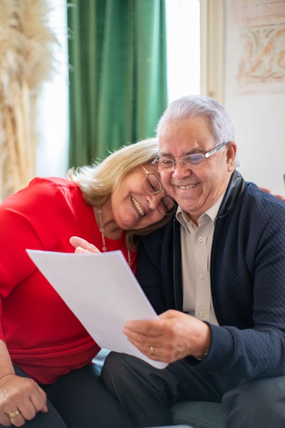 Couple souriant qui relit un document dans son salon